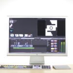 A sleek computer monitor displays video editing software in a modern workspace.